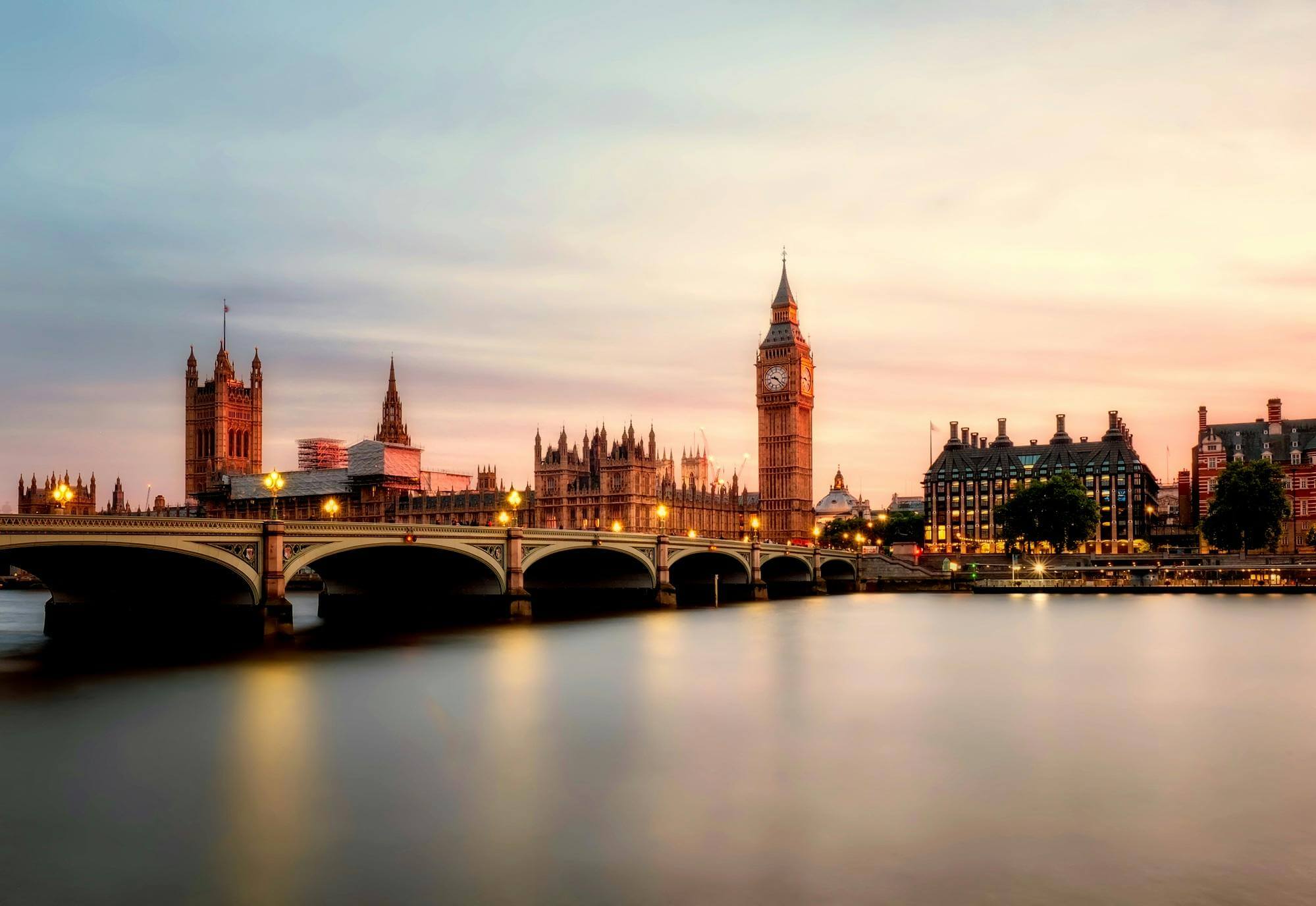 Big Ben and Westminster Bridge at sunset with the River Thames in the foreground.