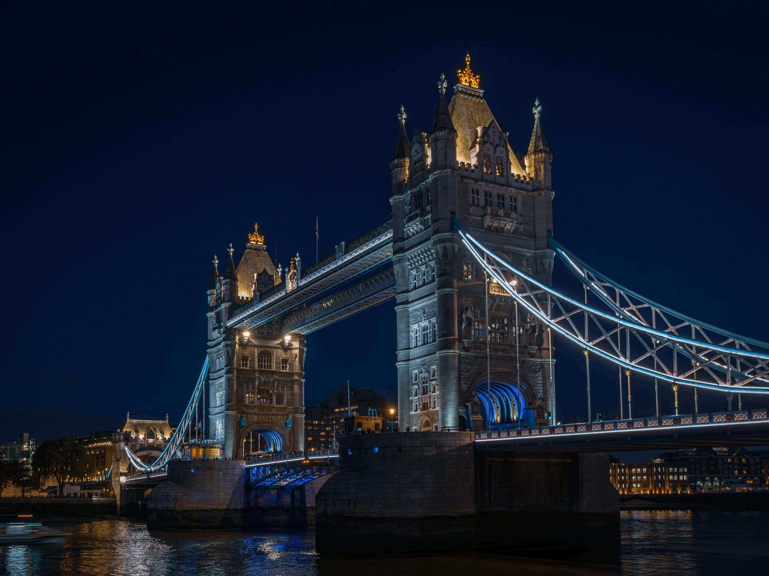"Tower Bridge lit up at night, spanning across the River Thames with city lights in the background."